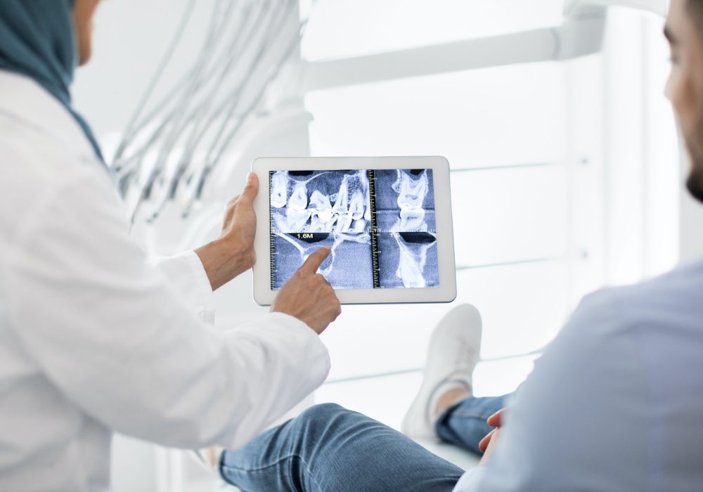 Oral Surgery. Female Dentist In Hijab Demonstrating Teeth Xray On Digital Tablet
